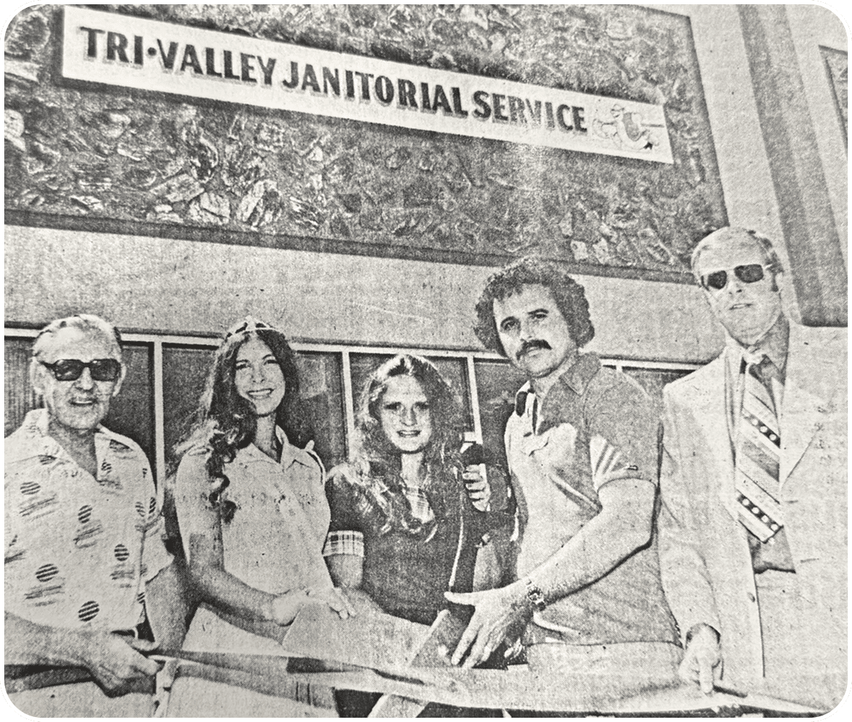 Group holding a ribbon at janitorial service.