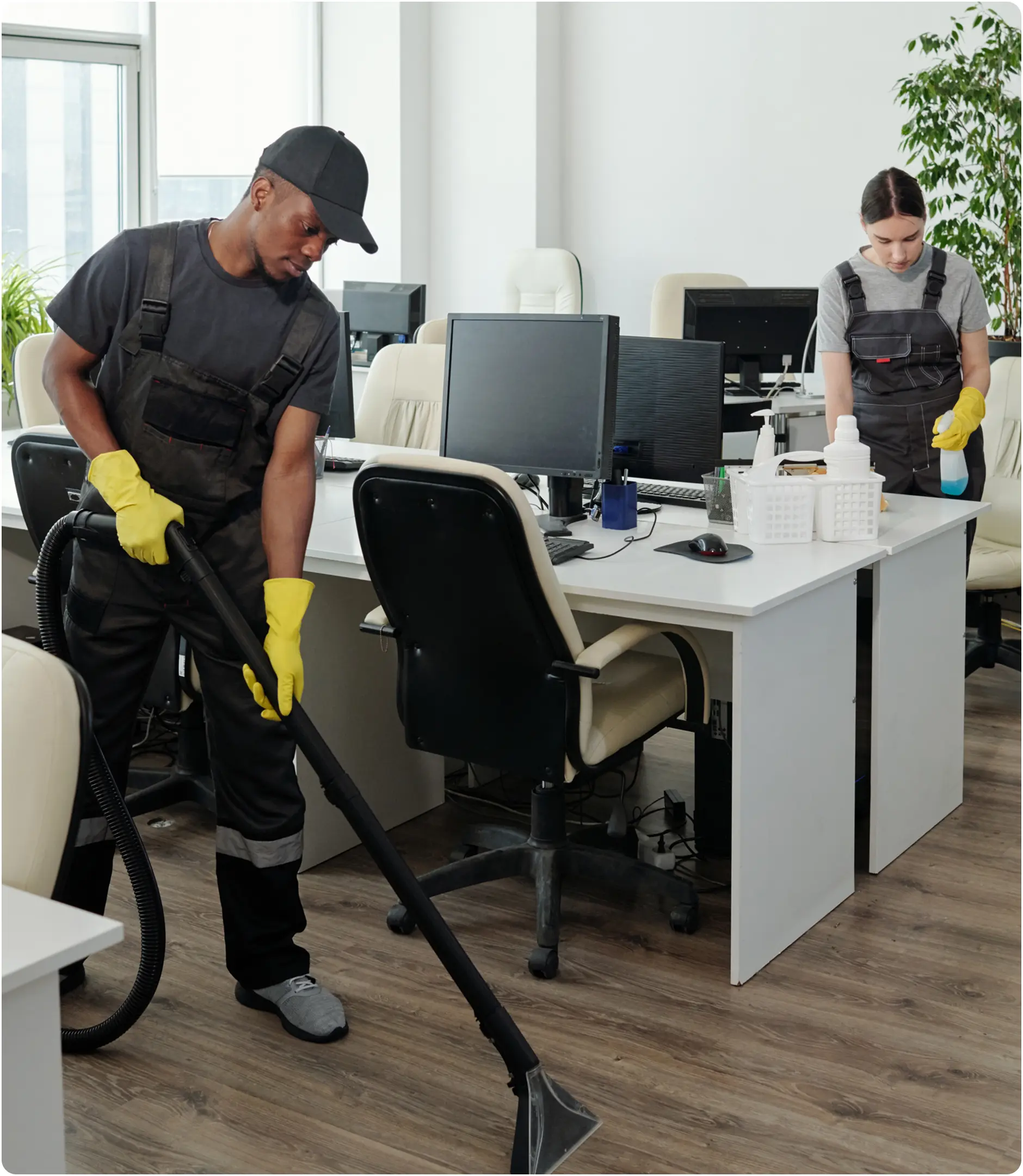 Office cleaning staff vacuuming and wiping desks.
