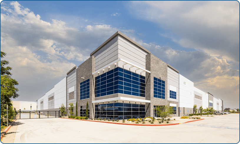 Modern industrial warehouse under a cloudy sky.